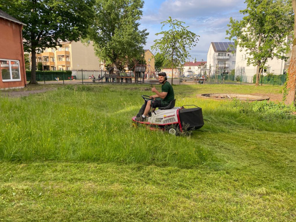 Mitarbeiter von ZAKO Gartenservice auf einem Aufsitzrasenmäher auf der Wiese